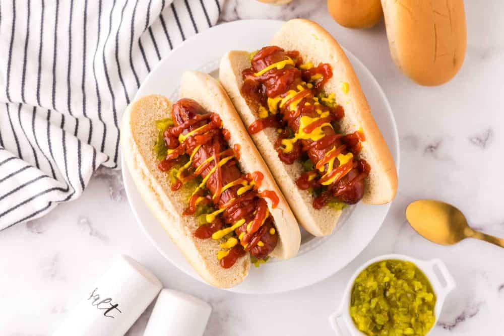 top view with two brats with ketchup mustard and relish in a traditional bun.