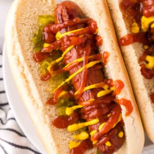 close up brats with ketchup mustard and relish in a traditional bun