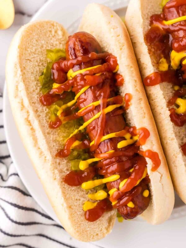 close up brats with ketchup mustard and relish in a traditional bun