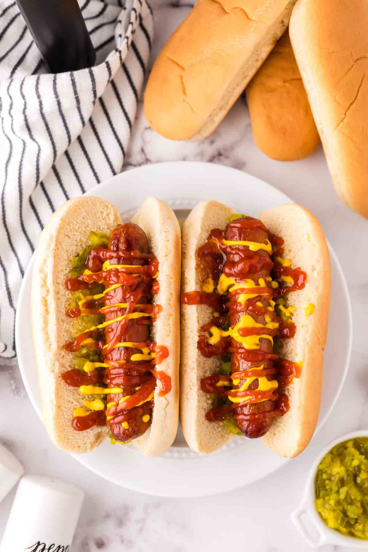 top view with two brats with ketchup mustard and relish in a traditional bun