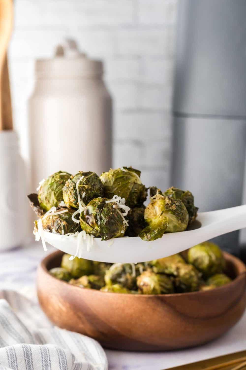 small wooden bowl with air fryer brussel sprouts with a white spoon