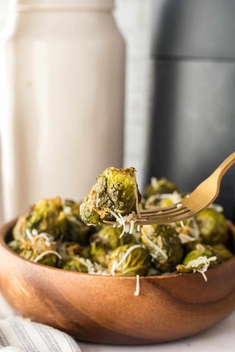 forkful over a small wooden bowl with air fryer brussel sprouts