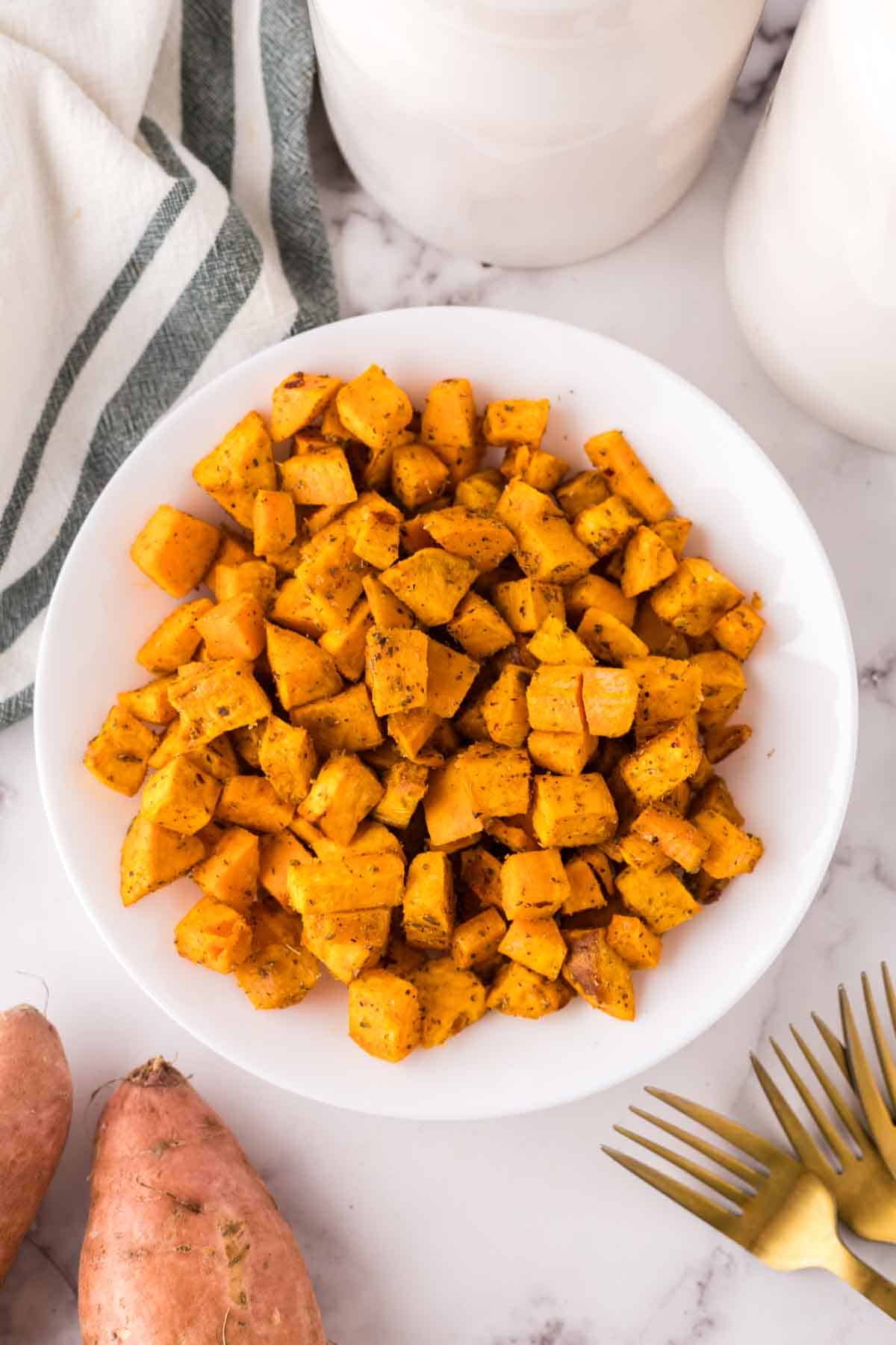 white plate of cooked and seasoned air fryer sweet potato cubes