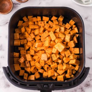 uncooked squares of sweet potatoes in the air fryer basket