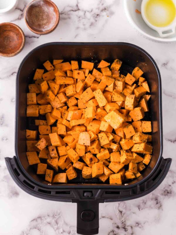 uncooked squares of sweet potatoes in the air fryer basket