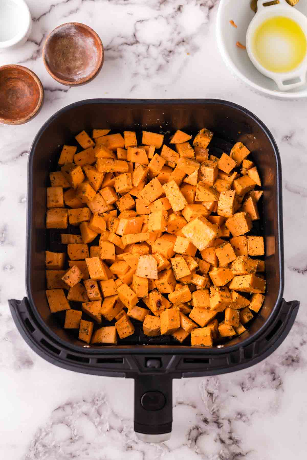 uncooked squares of sweet potatoes in the air fryer basket