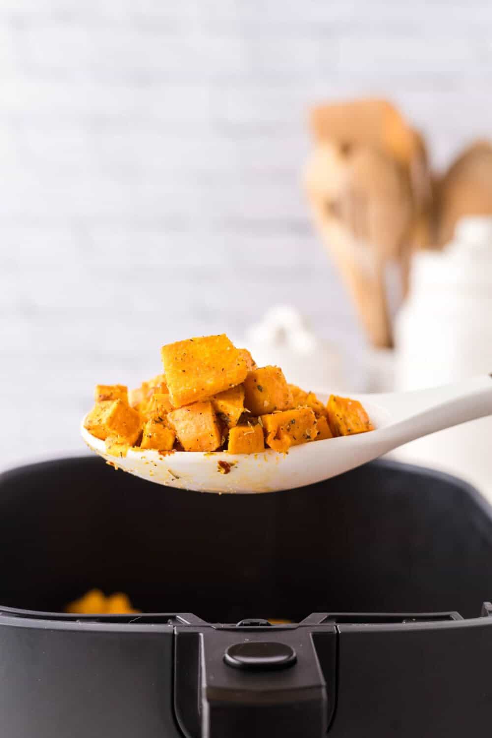 side view of spoonful of air fryer sweet potato cubes hot out of the basket