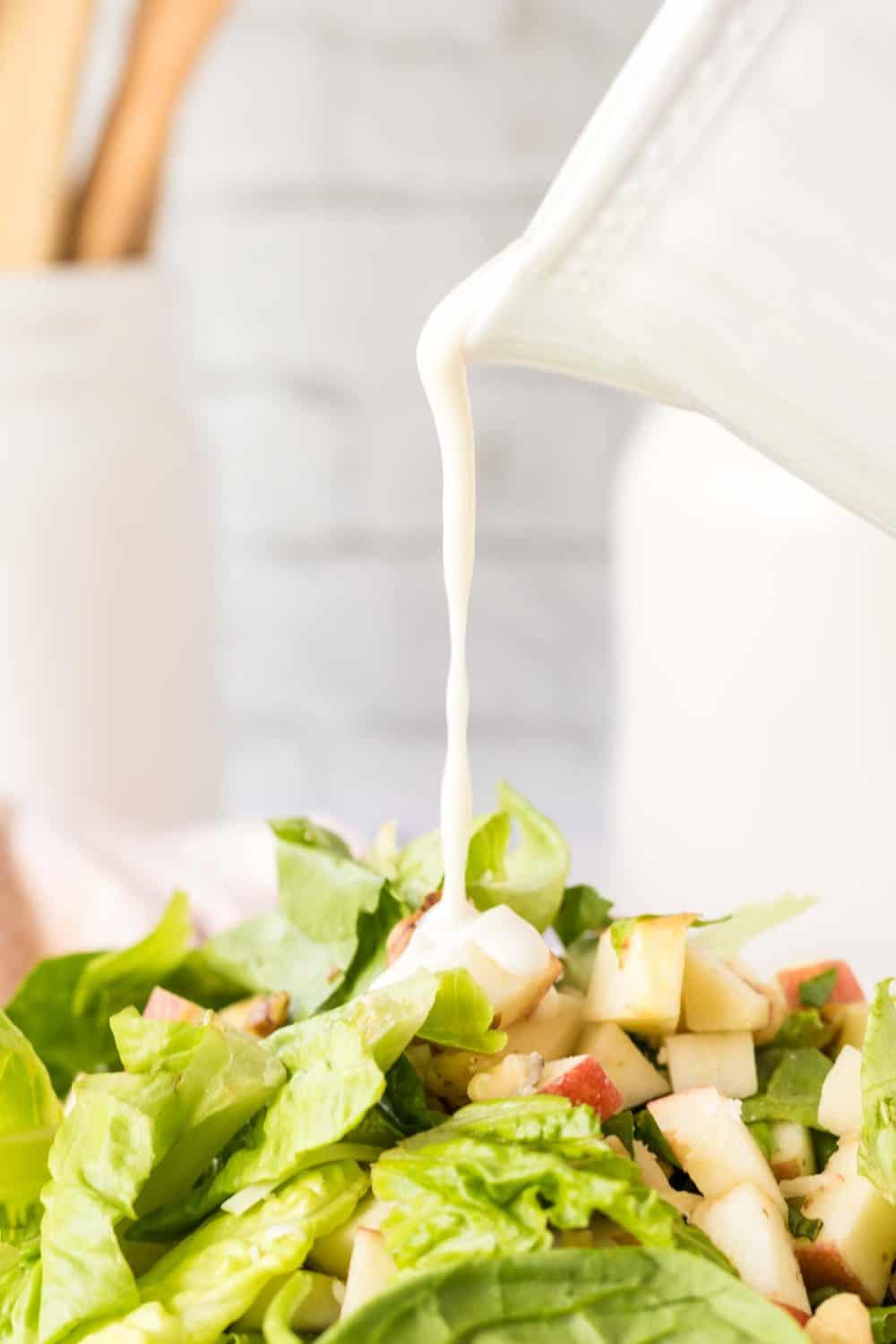 close up of apple salad and dressing being poured over top
