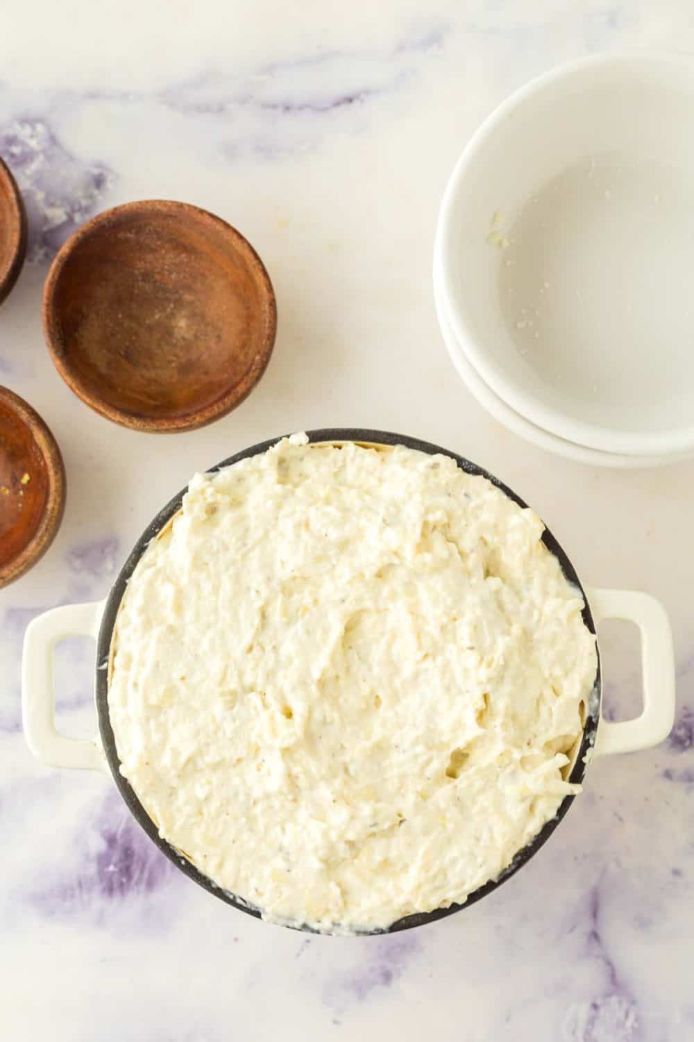 clear mixing bowl of the ingredients for artichoke dip recipe