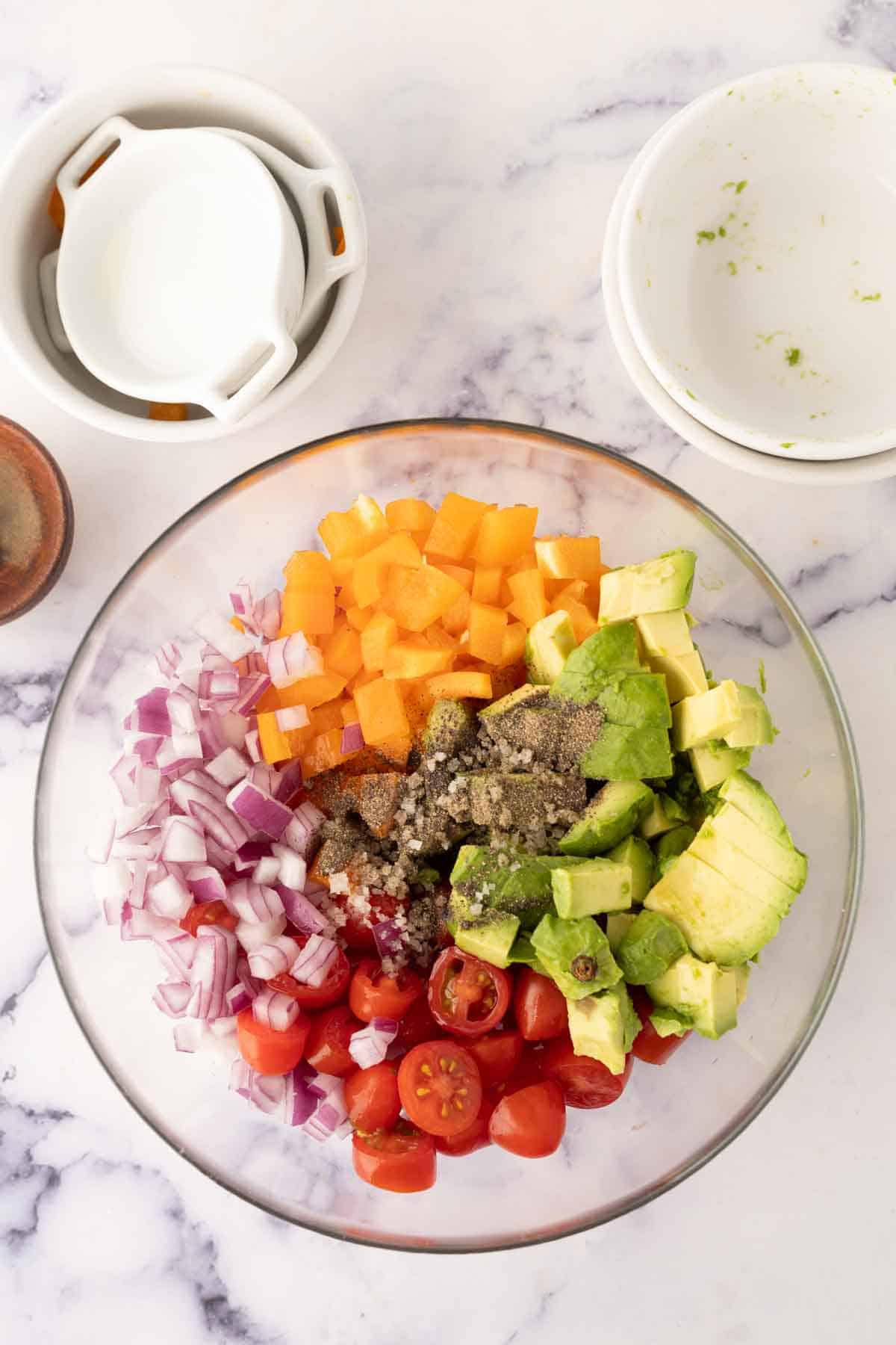 clear mixing bowl with ingredients for the avocado salad recipe