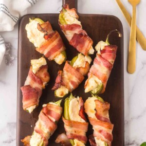 top view of baked bacon wrapped jalapeno poppers on a wooden board