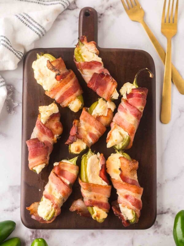 top view of baked bacon wrapped jalapeno poppers on a wooden board