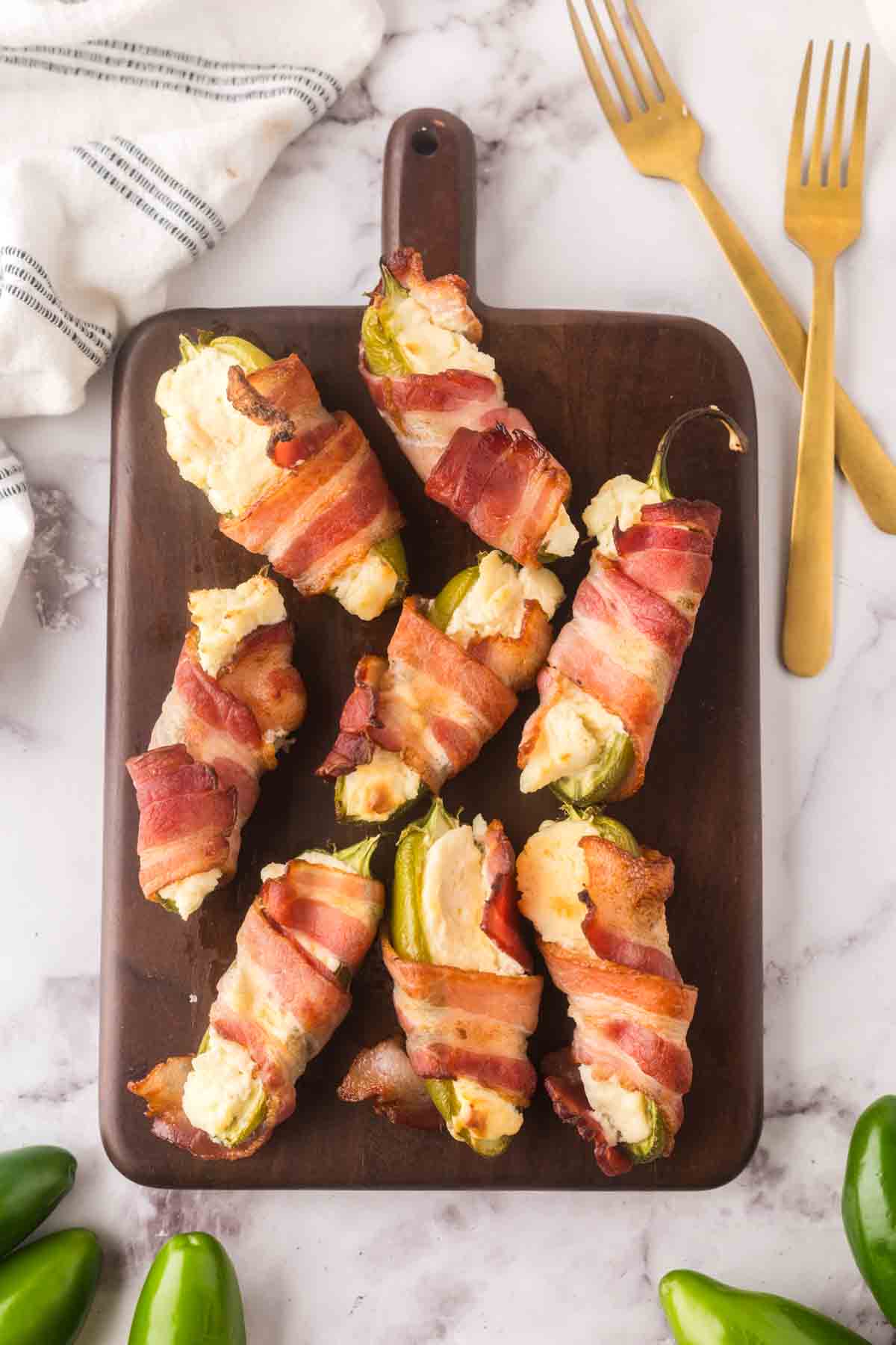 top view of baked bacon wrapped jalapeno poppers on a wooden board