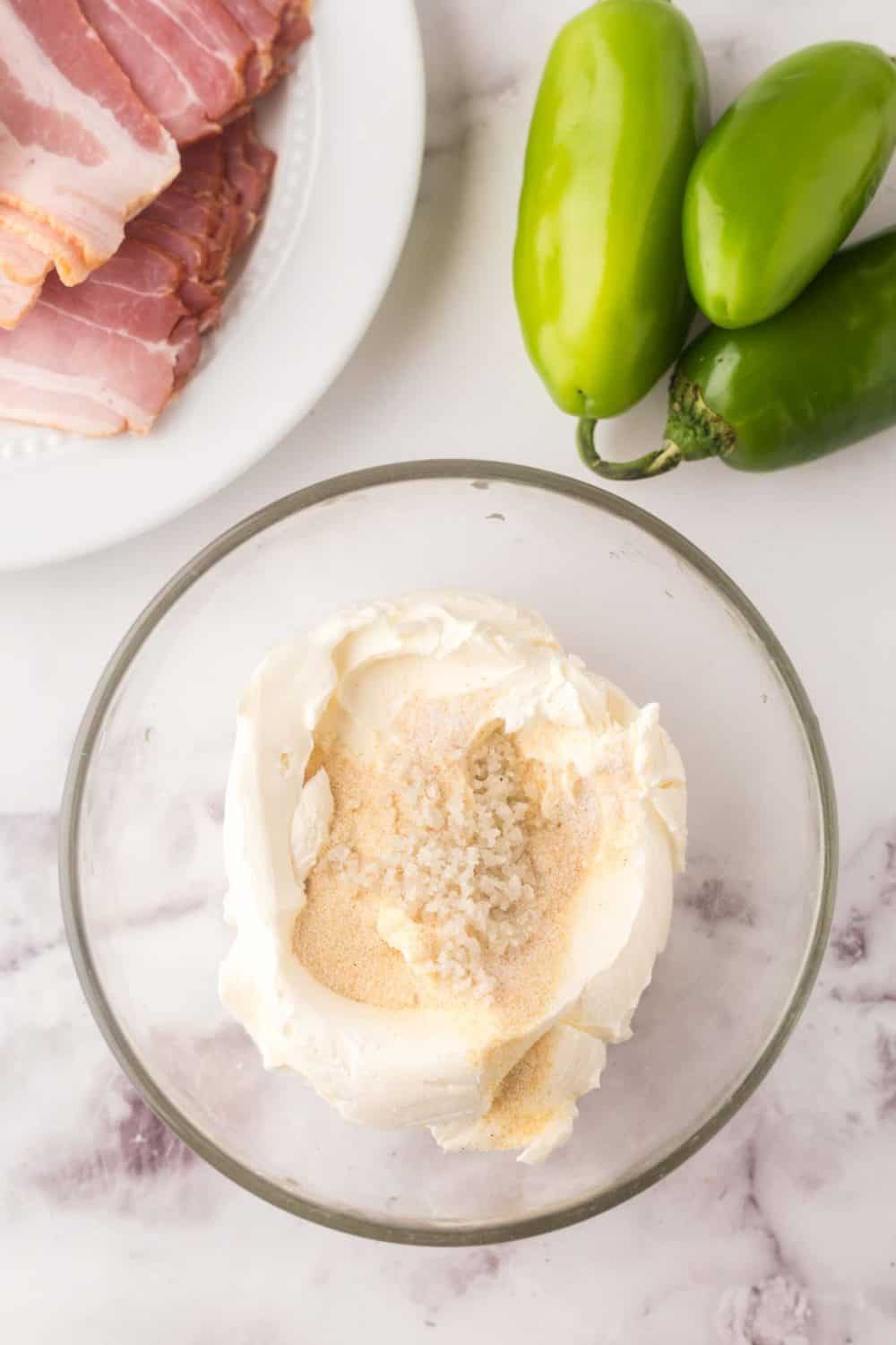 clear glass mixing bowl with stuffing for bacon wrapped jalapeno poppers