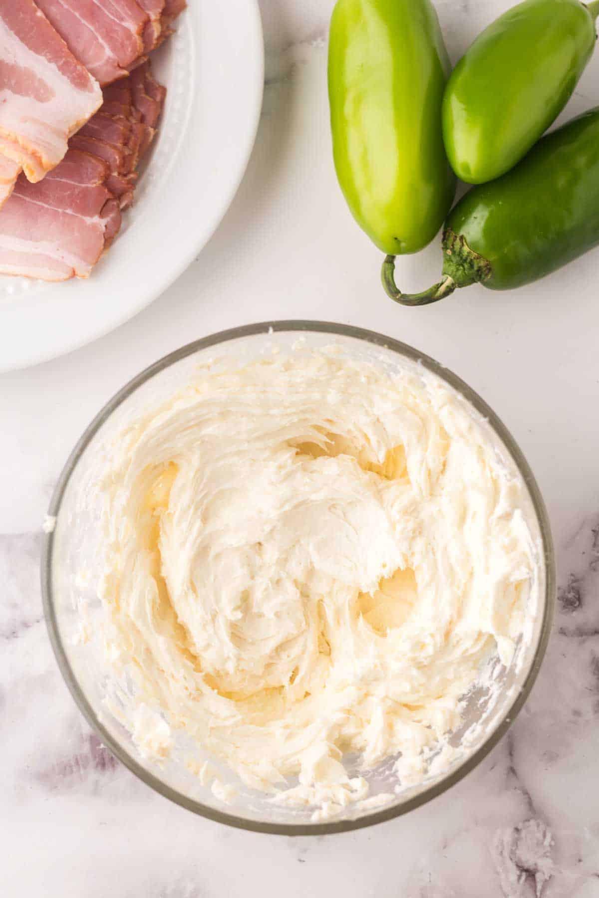 clear glass mixing bowl with stuffing for bacon wrapped jalapeno poppers