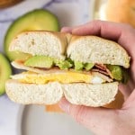 POV hand holding a side view of a half bagel sandwich