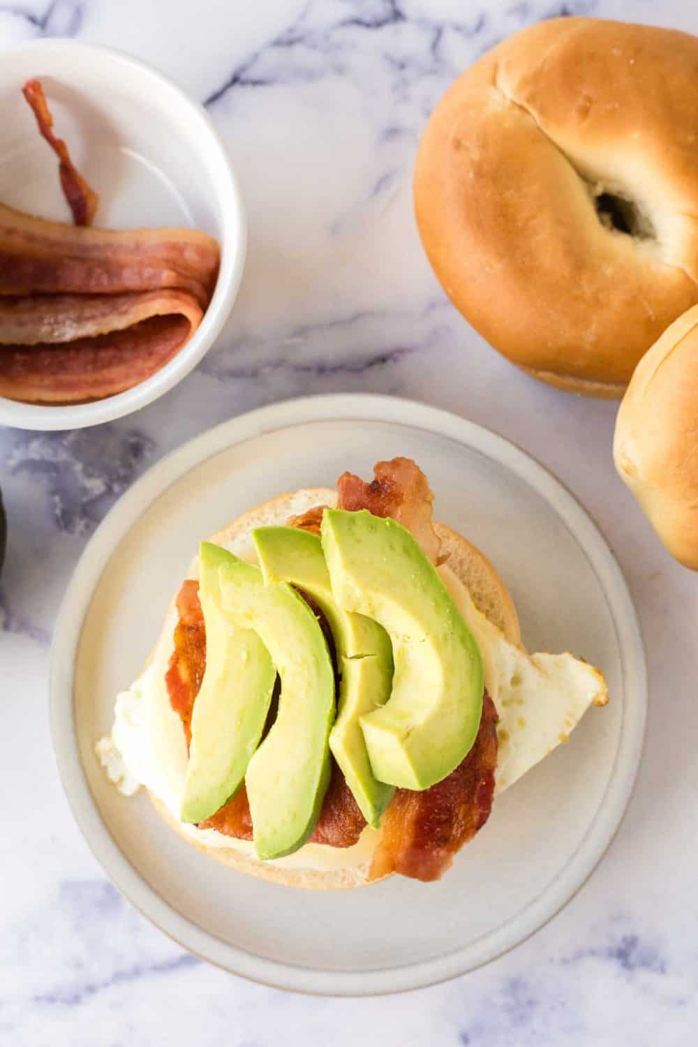 bagel with an egg then cheese bacon and avocado on top