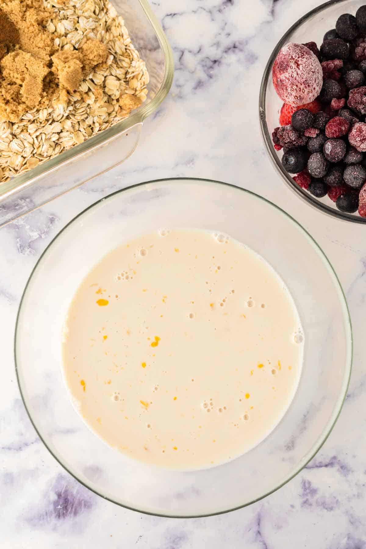 clear mixing bowl with baked oatmeal ingredients