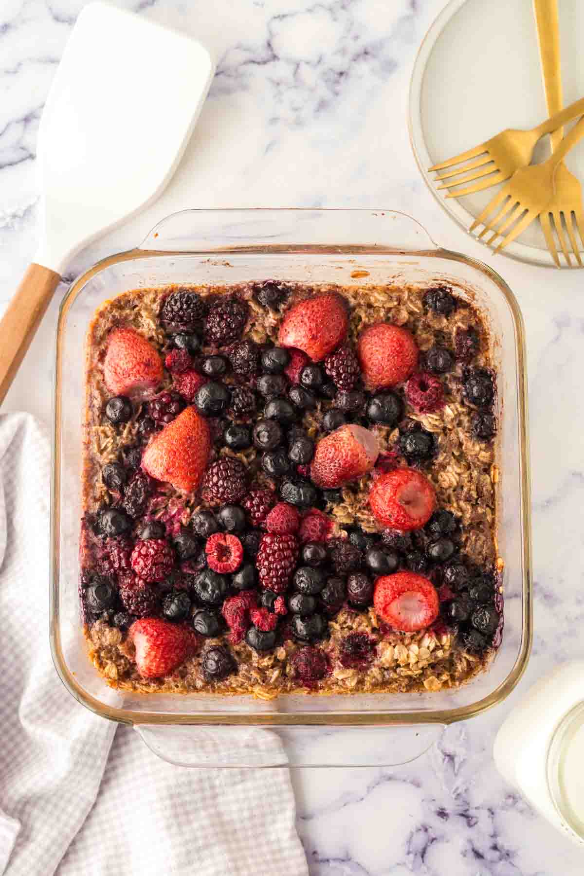 clear square casserole dish with baked oatmeal berries baked to a golden brown