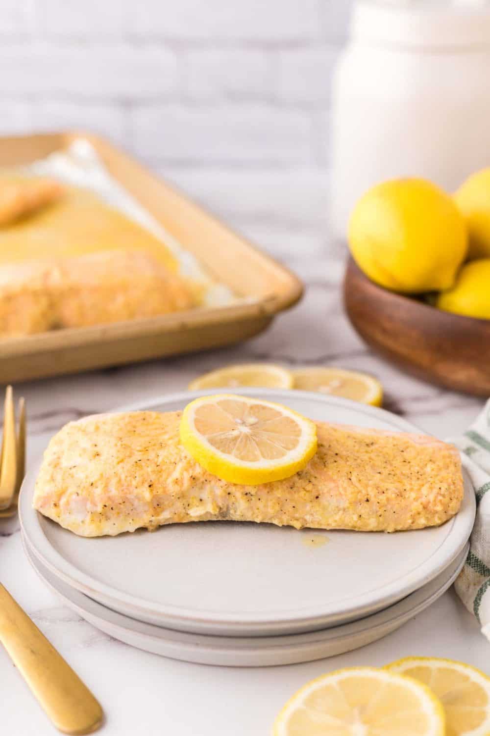 baked salmon in foil recipe with a lemon on top over a round plate