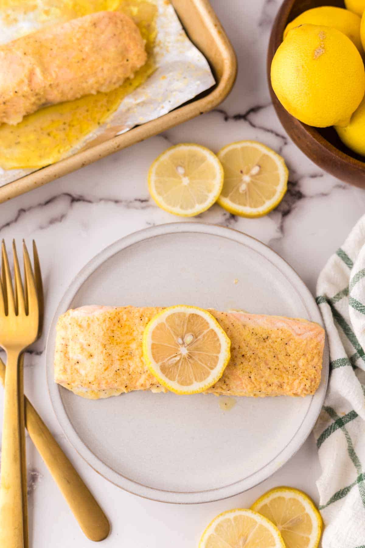 baked salmon in foil recipe with a lemon on top over a round plate