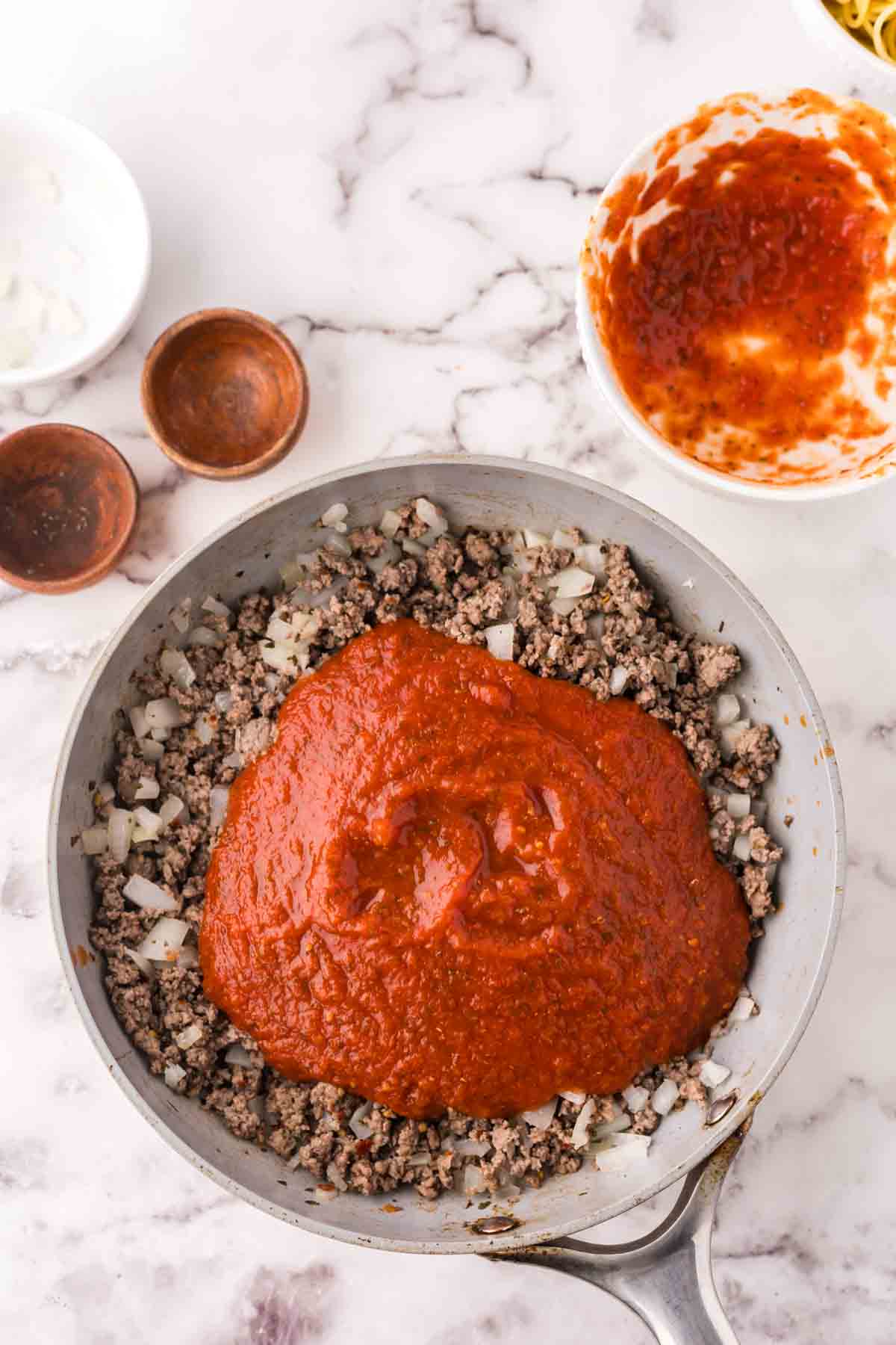 Red sauce added to a pan of browned ground beef.