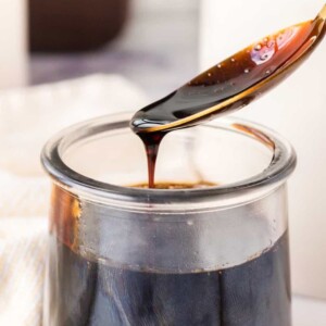 spooning a sticky drip of balsamic glaze from a small glass dish