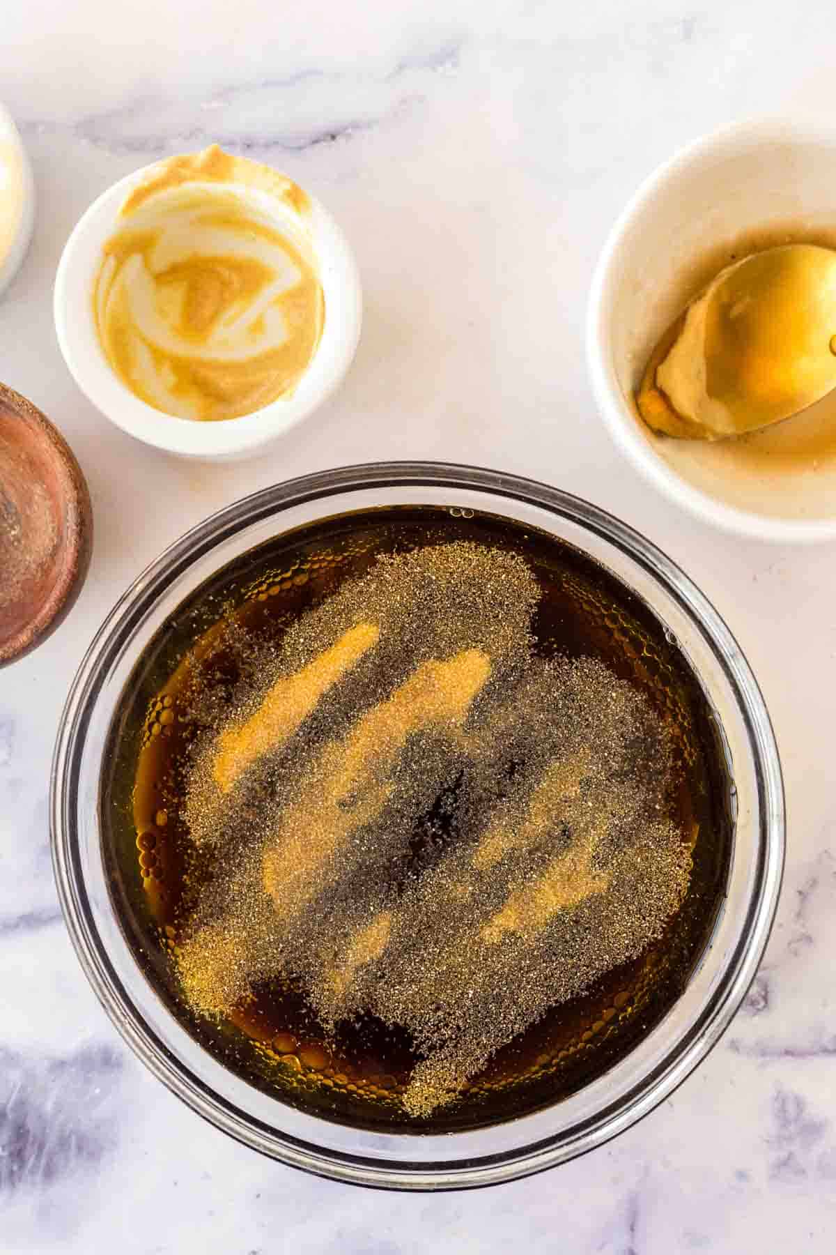 clear mixing bowl with stages of the ingredients added for balsamic vinaigrette