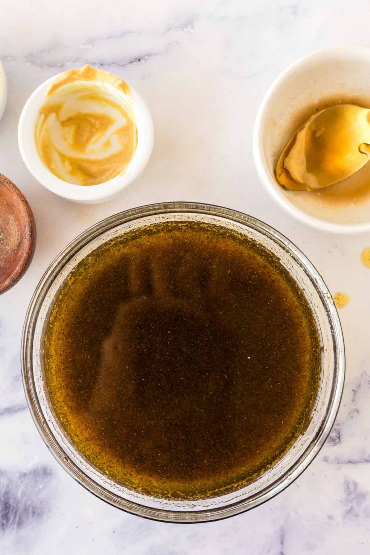 clear mixing bowl with stages of the ingredients added for balsamic vinaigrette