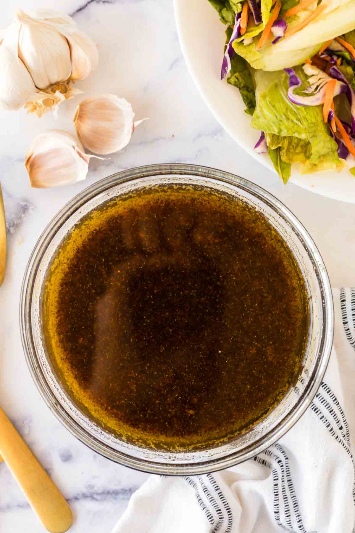 clear mixing bowl with stages of the ingredients added for balsamic vinaigrette