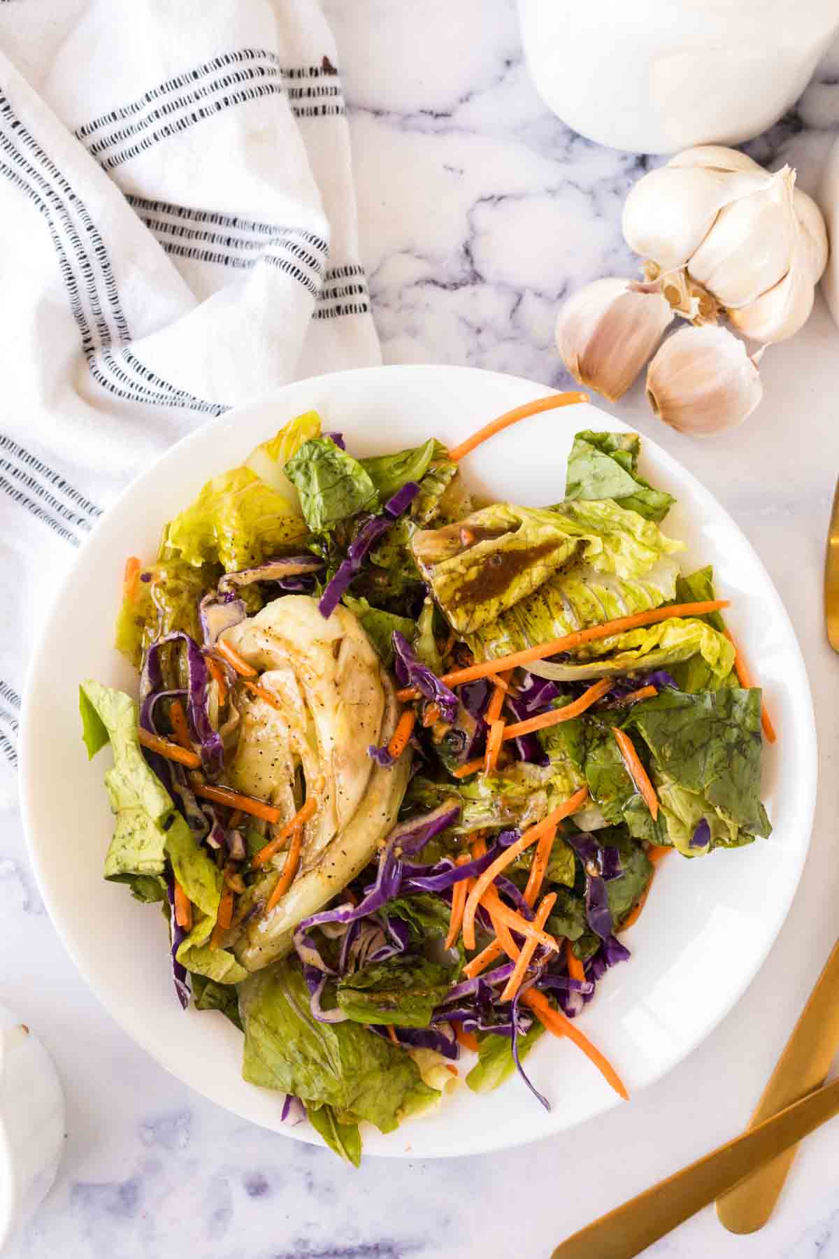 top view of a salad dressed with balsamic vinaigrette on a round white plate