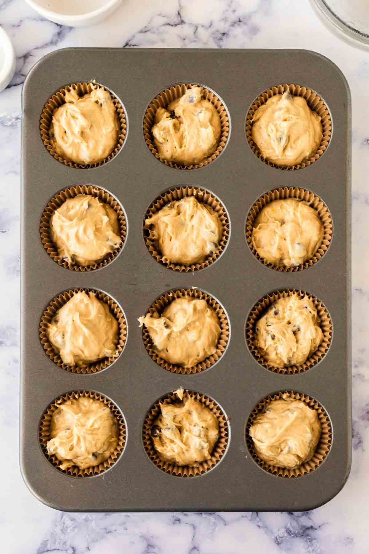 muffin tins with banana chocolate chip muffin batter