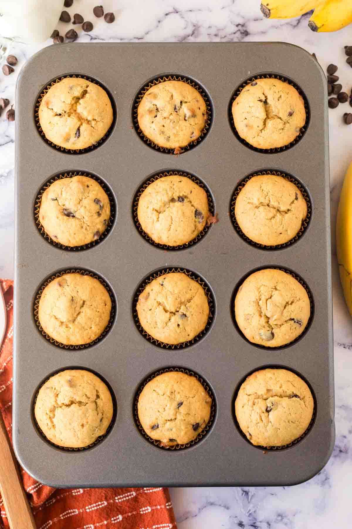 top view of a muffin tin with baked banana chocolate chip muffins