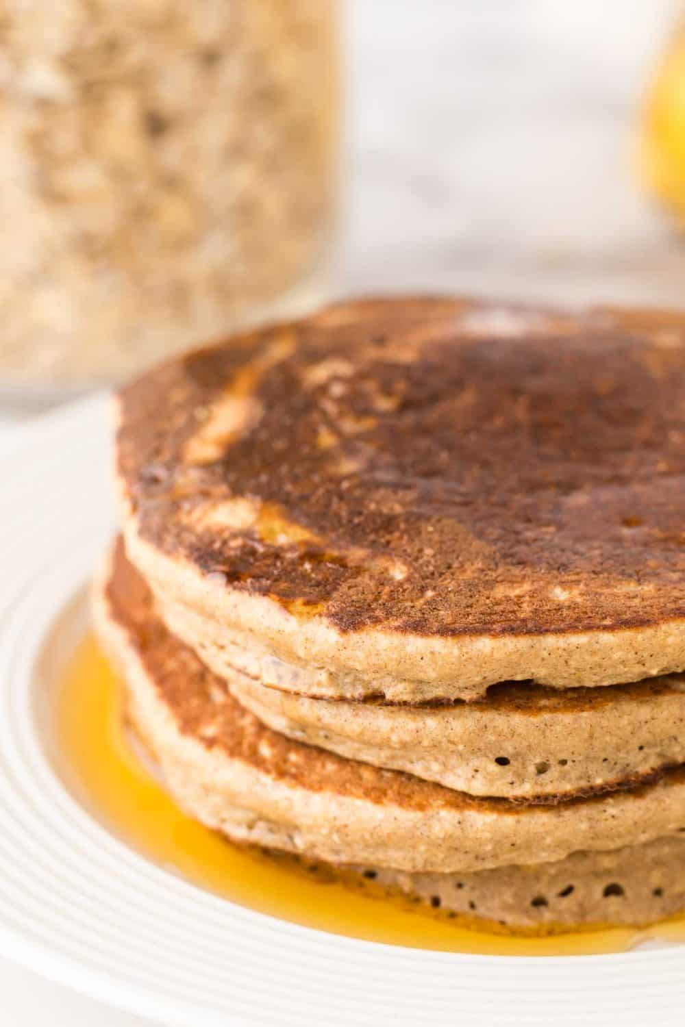 a stack of banana oatmeal pancakes on a white plate with syrup on top