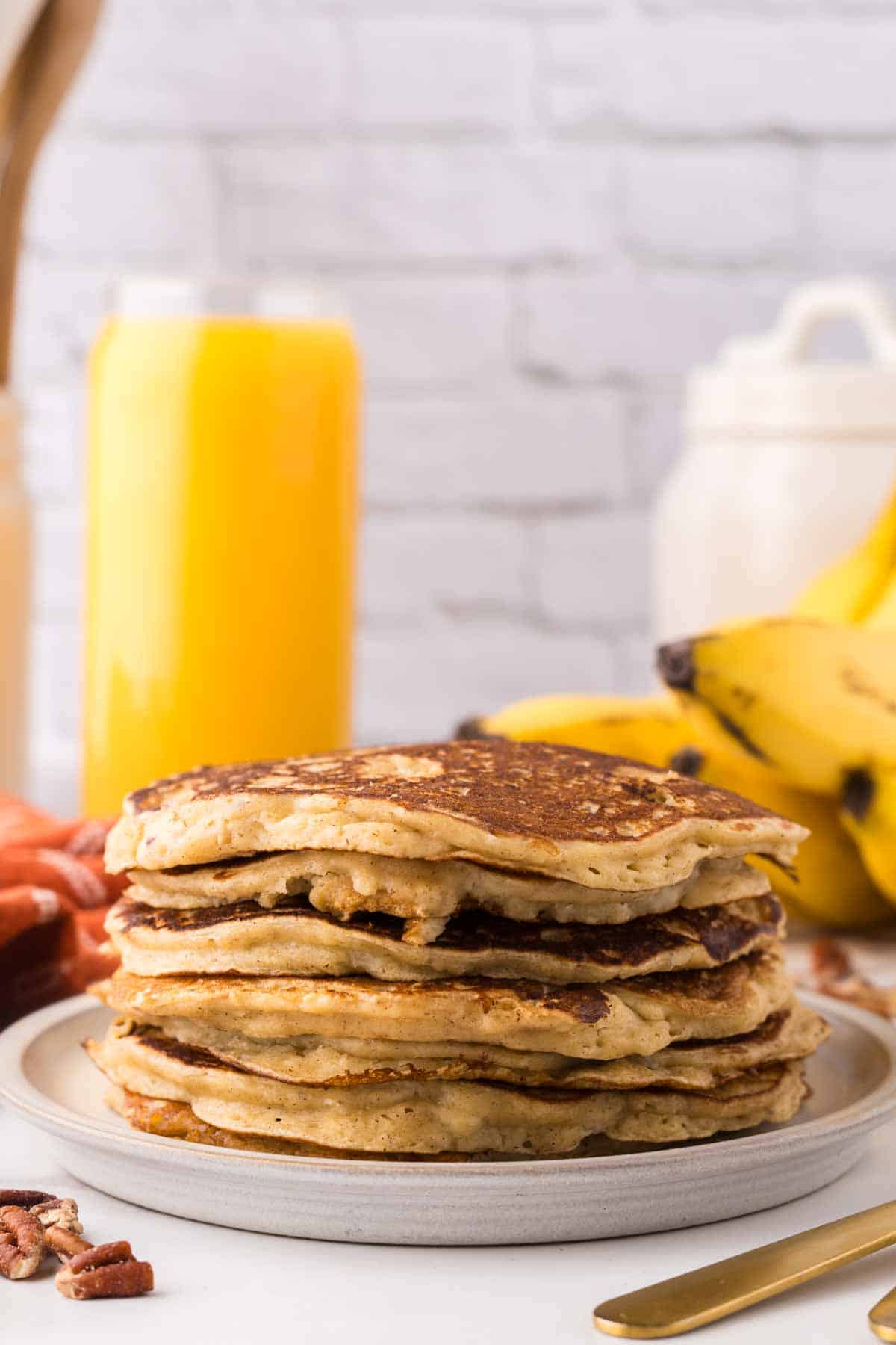 side view of a stack of banana pancakes on a round plate