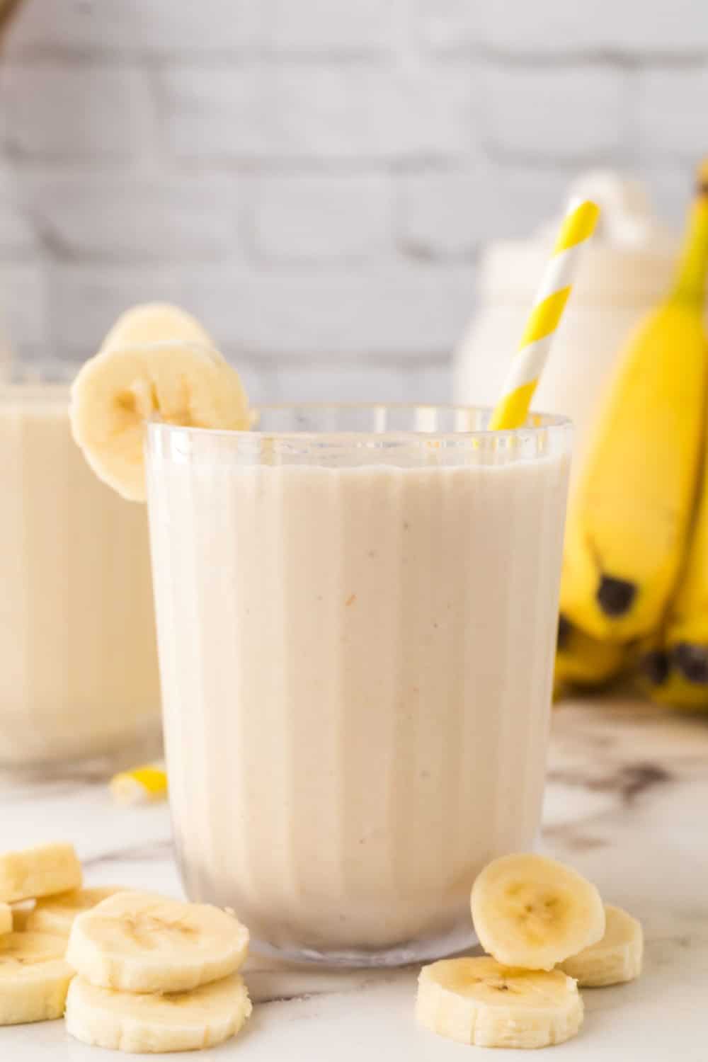 Banana smoothie ready to enjoy with slices of bananas around it.