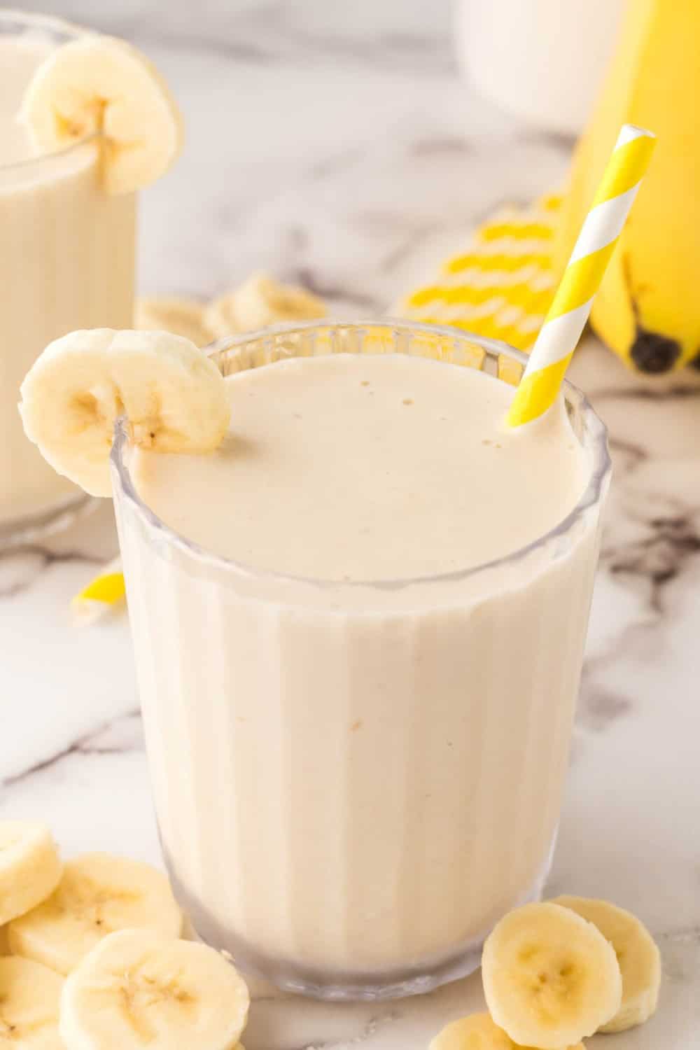 Delicious banana smoothie in a glass with a straw.