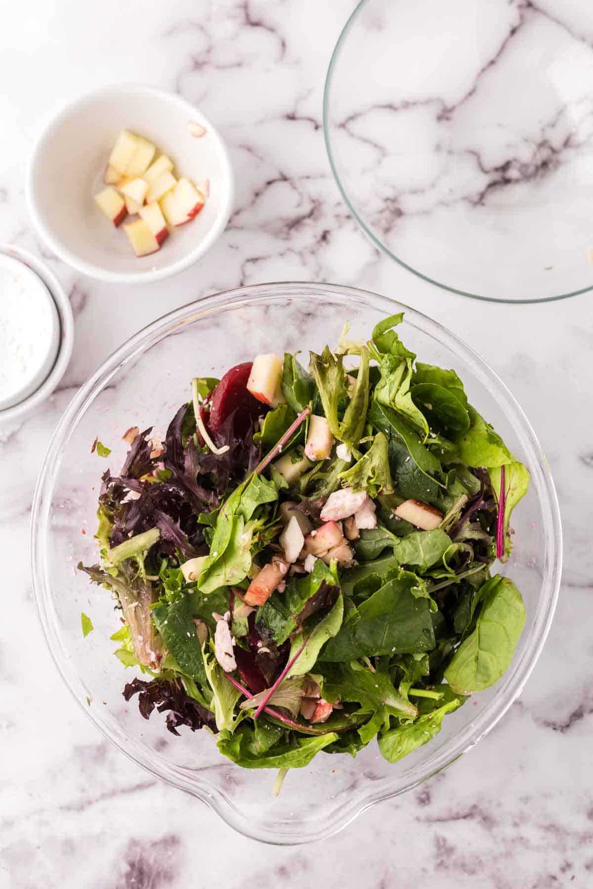 Beet salad in a clear glass bowl in progress.