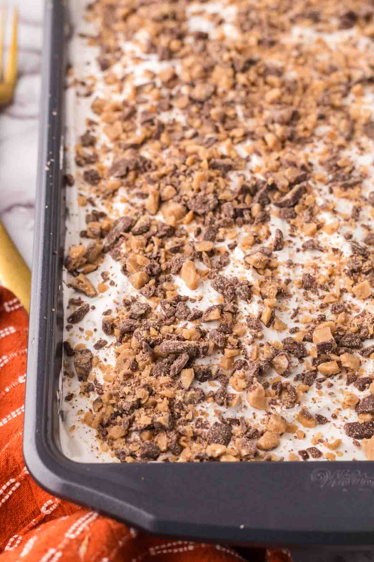 very close up of a corner of the pan of better than sex cake recipe baked and whole in the pan iced and garnished