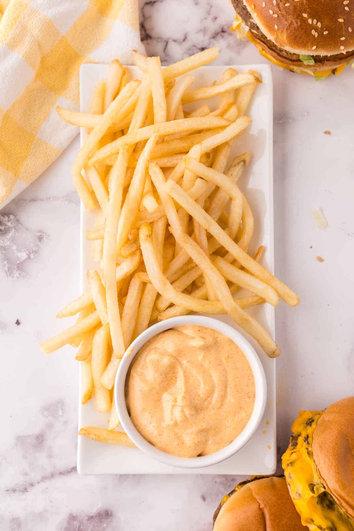 a small dish of mac sauce on a long rectangle plate of french fries
