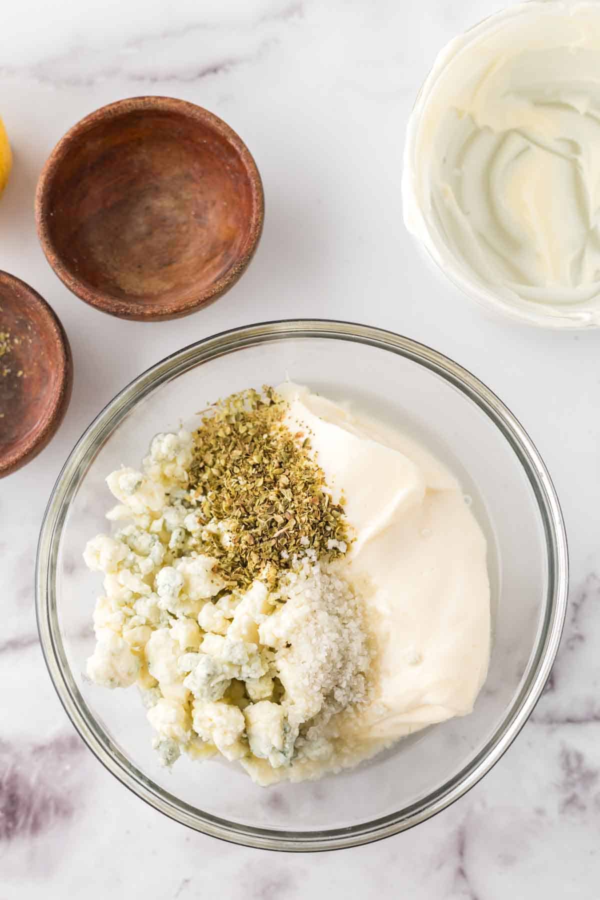 clear mixing bowl with ingredients for blue cheese dressing recipe