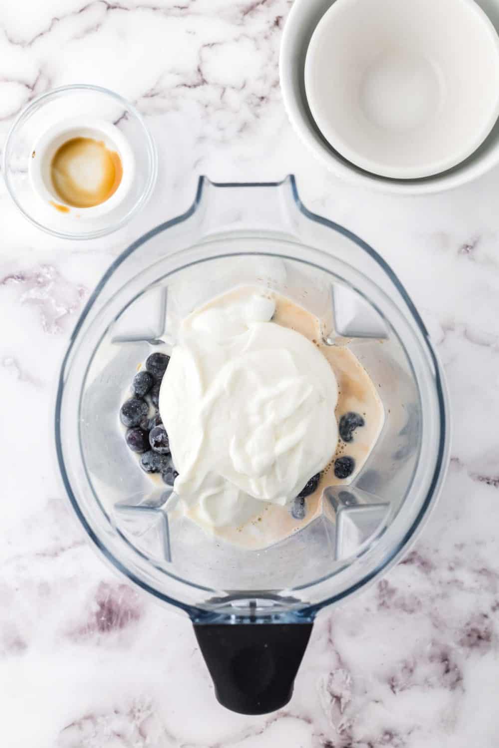 top view into a blender of blueberry smoothie ingredients before blended