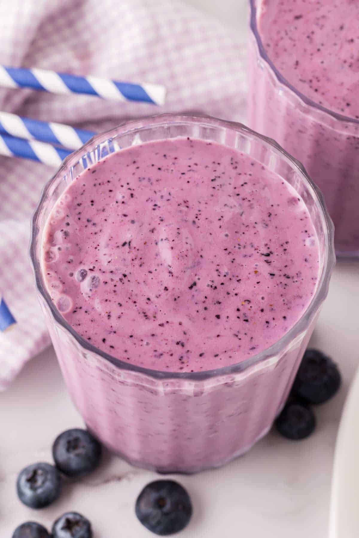 blueberry smoothies in nice ribbed glasses with blue striped paper straws