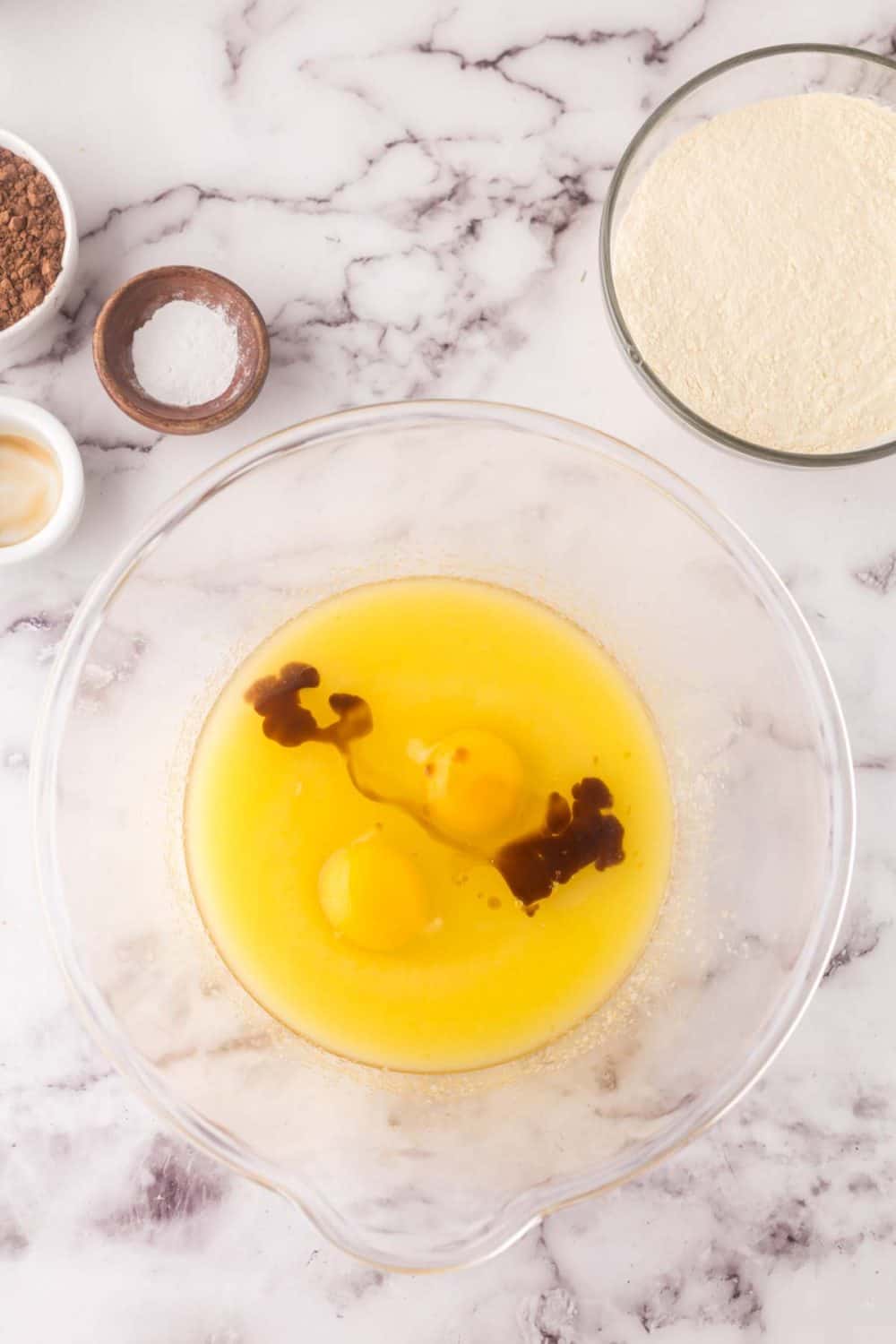 clear mixing bowl with ingredients in steps being added for brownie cookie batter