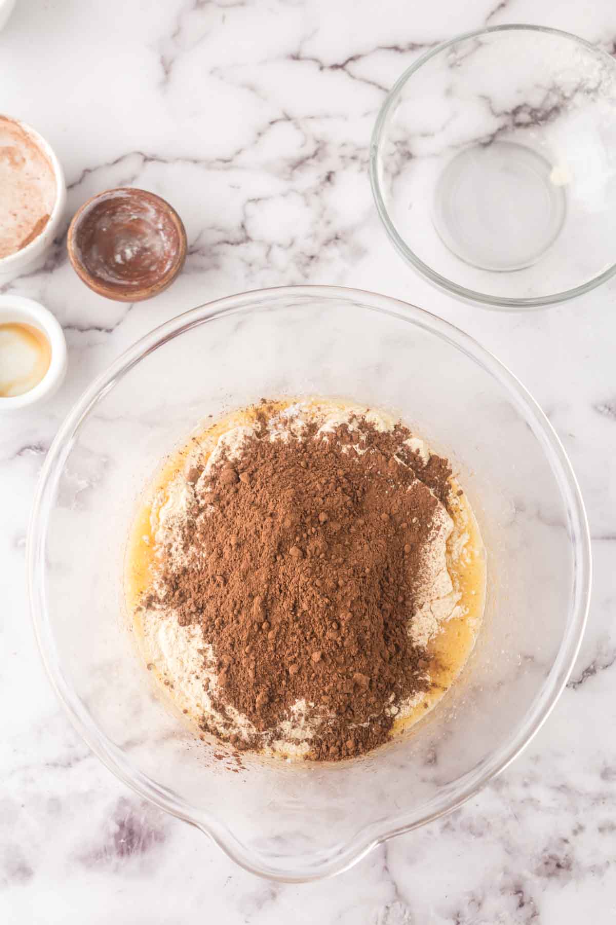 clear mixing bowl with ingredients in steps being added for brownie cookie batter