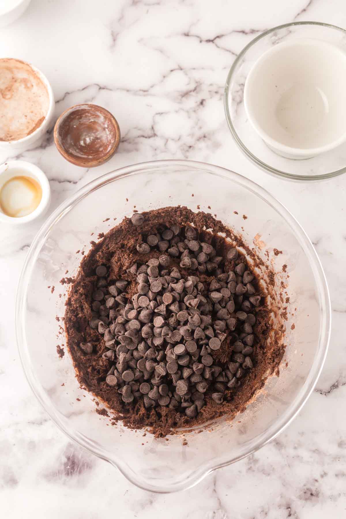 clear mixing bowl with ingredients in steps being added for brownie cookie batter