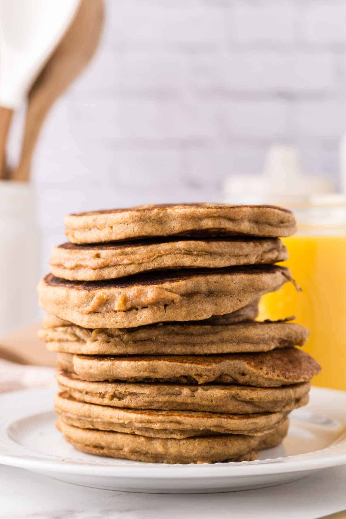 side view of a tall stack of buckwheat pancakes on a white plate