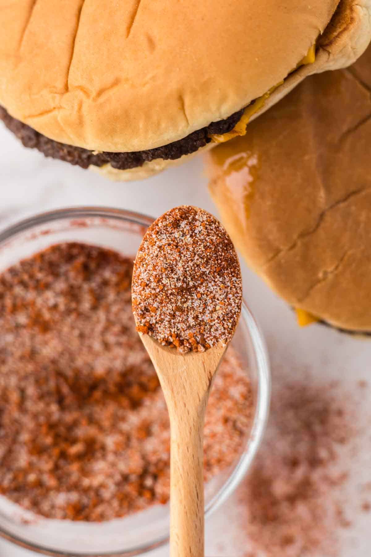 burger seasoning in a clear mixing bowl with a wooden spoon