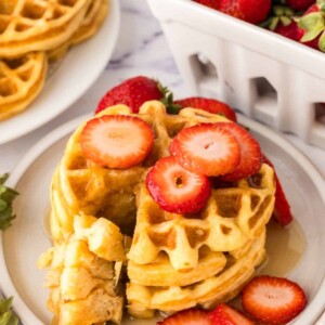 a stack of buttermilk waffles syrup and fresh strawberries
