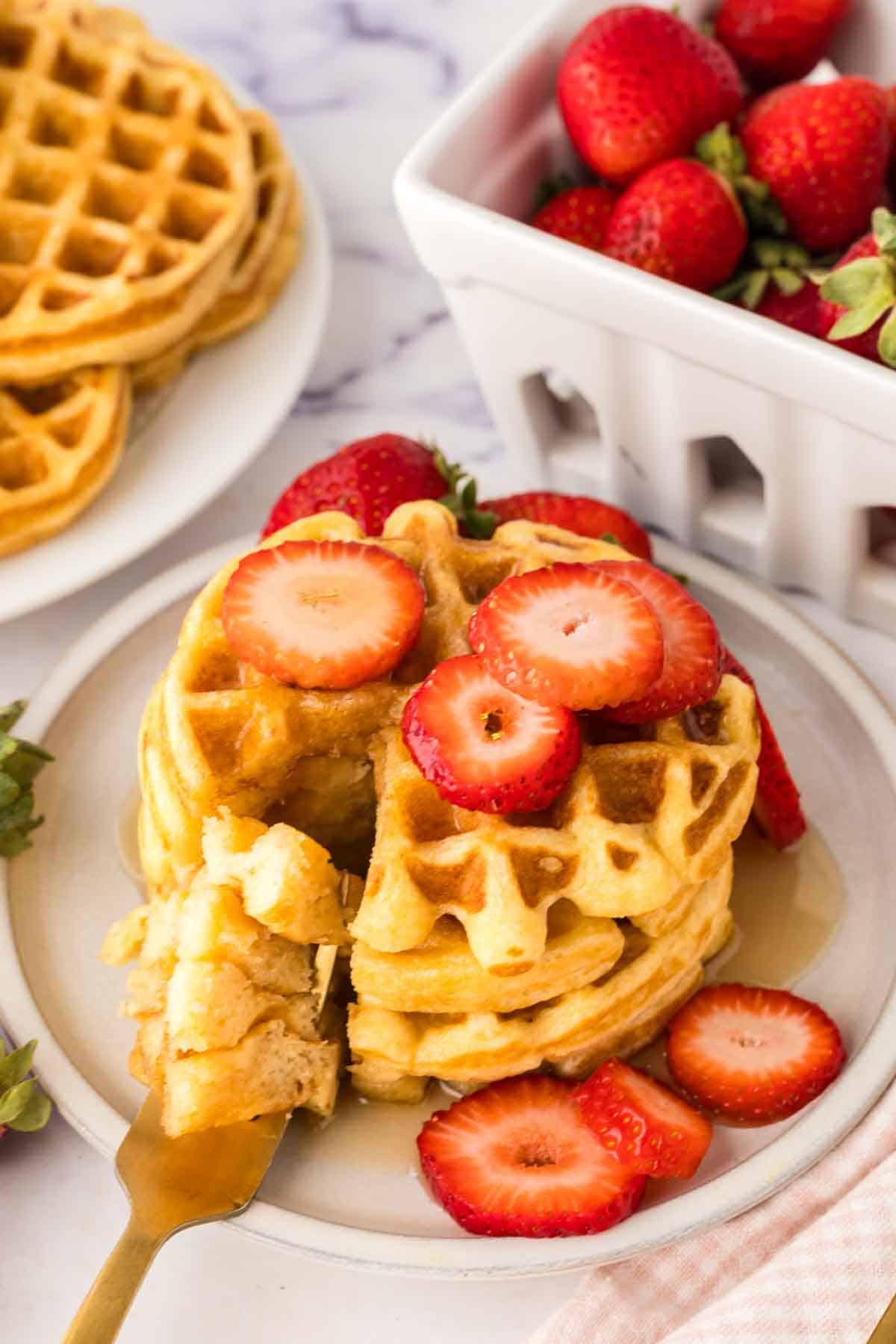 a stack of buttermilk waffles syrup and fresh strawberries
